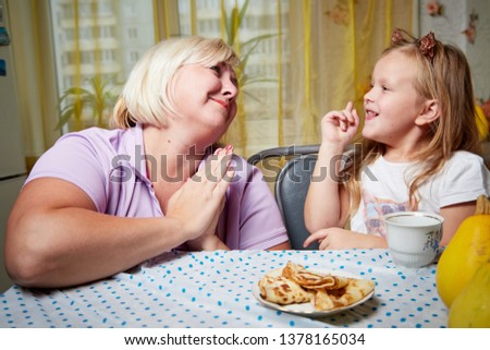 Adalt mother and her young daughter in a kitchen with pancakes. Top view