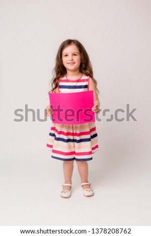 baby brunette girl holding blank sheet on white background, place for text