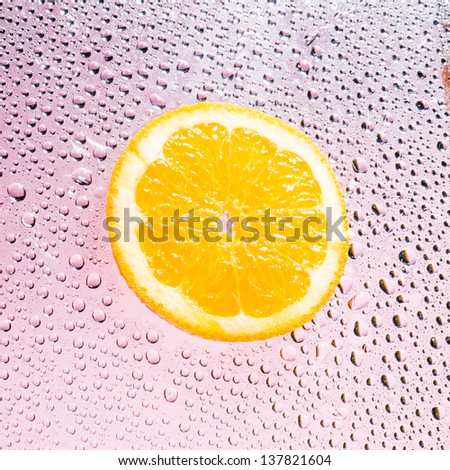 Orange fruit with water drops isolated on pink background.