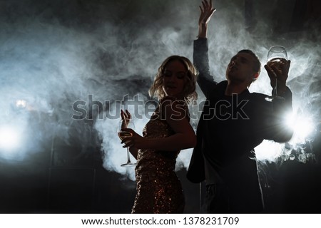 Silhouettes of a young couple dancing at a party.