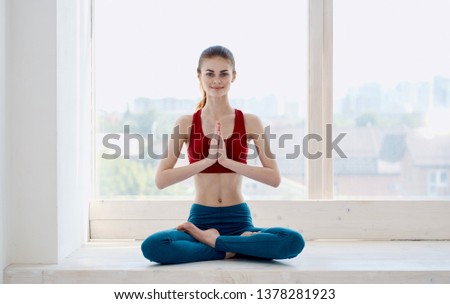 Athletic woman doing yoga on the windowsill meditation