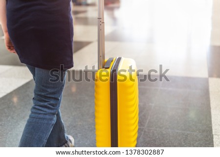 Girl is in the airport with bright and stylish cabin size suitcase as holiday concept. Easy travel with little baggage