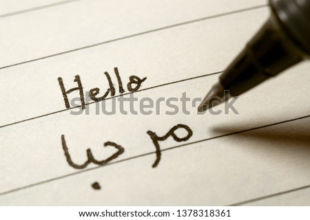 Beginner Arabic language learner writing Hello word in abjad Arabic alphabet on a notebook close-up shot