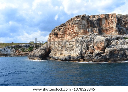 The view from the tourist boat on the rocky high coast and caves and the blue clear water of the Mediterranean Sea. The resort town of Calas de Mallorca on the Spanish island of Mallorca
