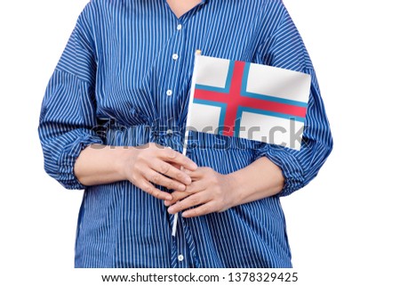 Faroe Islands flag. Close up of woman's hands holding a national flag of Faroe Islands isolated on white background.