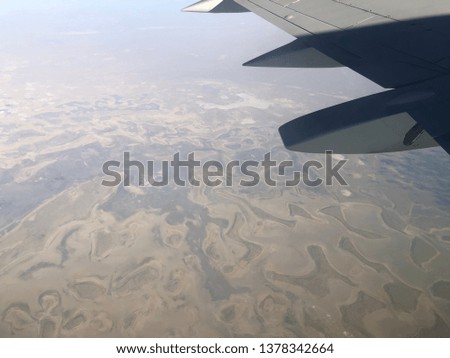 View from the plane window. Air transport. The hilly terrain and mountains view from altitude. Travelling by plane.