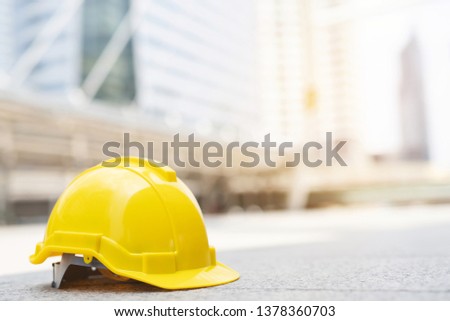 yellow hard safety wear helmet hat in the project at construction site building on concrete floor on city with sunlight. helmet for workman as engineer or worker. concept safety first. 
