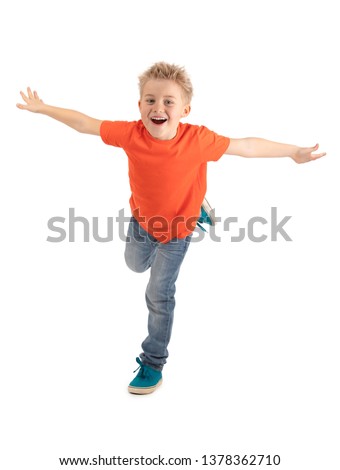 HAPPY BOY SMILING WHILE STANDING ON ONE LEG AND MAKING LIKE FLYING ISOLATED ON WHITE BACKGROUND