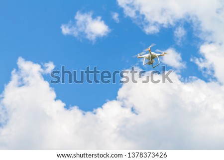 White drone quad copter with high resolution digital camera flying in the blue sky