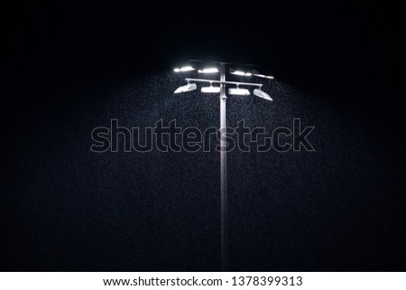 LED stadium lights at a rainy sports field, with a dark sky background, in a rain delay concept Royalty-Free Stock Photo #1378399313