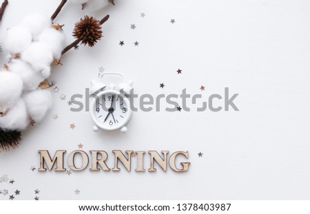 White table clock, alarm on white background, top view. Good morning. Minimalism, flatlay