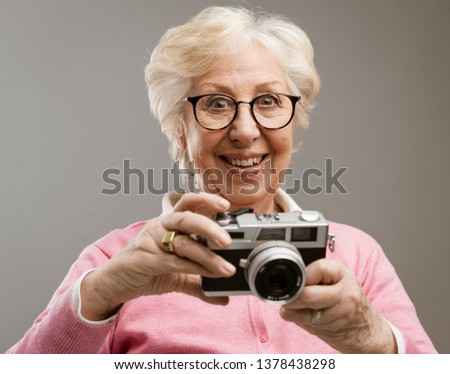 Cheerful happy senior woman using a digital camera, she is smiling