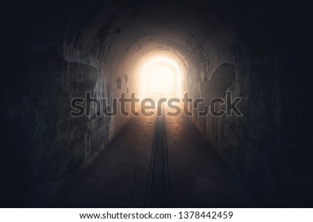 Light in end of tunnel. Long underground concrete corridor in abandoned bunker, toned. Tunnel in underground protective bunker. Protection against nuclear attack. Royalty-Free Stock Photo #1378442459