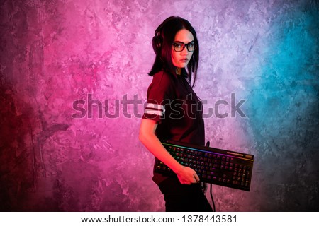 Funny nerd gamer girl posing with gaming keyboard, playing computer games