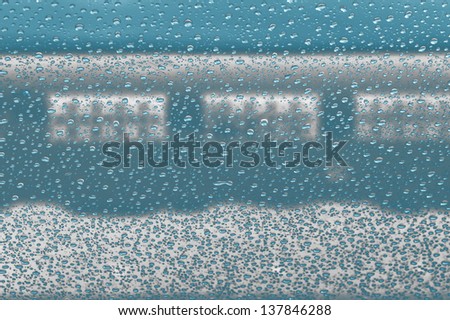 Clear raindrops on windscreen with blue cloudy sky background rendered in  light blue neon glow   ideal for  unique abstract wallpapers.