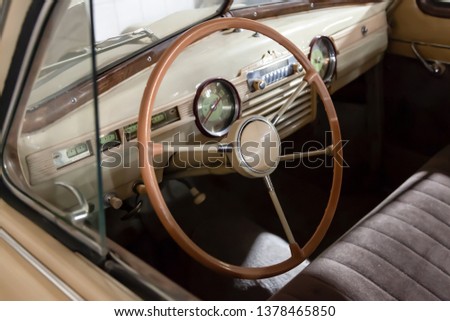 View on opened window with the steering wheel and the interior of the old Russian retro vintage car of the executive class released in the Soviet Union beige