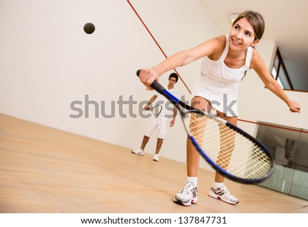 Beautiful woman playing a match of squash Royalty-Free Stock Photo #137847731
