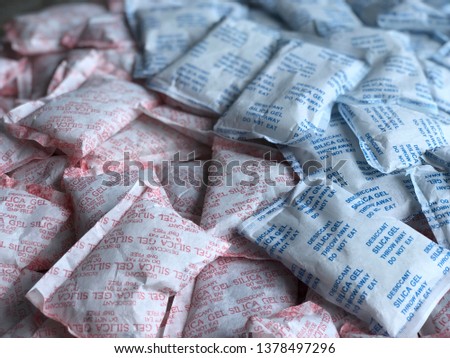 Multiple Desiccant silica gel packets, with dark tone, used for moisture protection in the food industry, on packaging has the label clearly labeled "Desiccant, Silica gel, Throw Away, Do not eat".