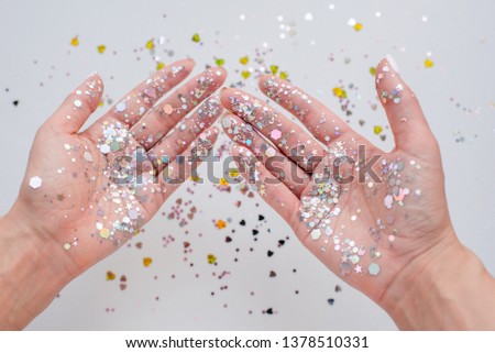 The hands of the girl in the sparkles. Festive happy mood. Party and event for girls. Celebrate the holiday, open the gift. Hands close up. Magic moment. Fashion and beauty concept. Glitter elements