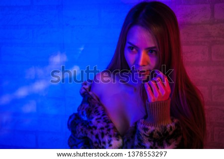 Fashion model brunette woman in colourful bright sparkles and neon lights posing in studio, portrait of beautiful girl,  Vivid neon red-blue makeup,trendy glowing make-up. Art design colorful make up.