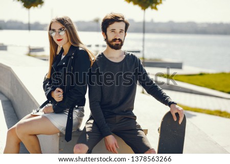 young hipsters sitting in a summer sunny park with a skateboard in their hands