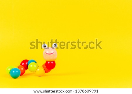 Colorful wooden baby toy worm on yellow background