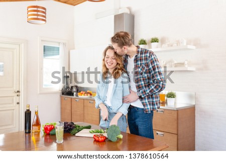 Young couple in casual clothes preparing a vegetable salad and smoothie. Concept of vegetarianism and proper nutrition
