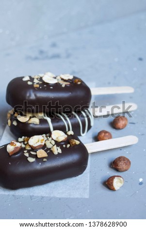 Chocolate ice cream with nuts on a stick on a gray background. Chocolate Popsicle Cakes