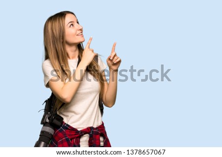 Young photographer woman pointing with the index finger and looking up on isolated blue background