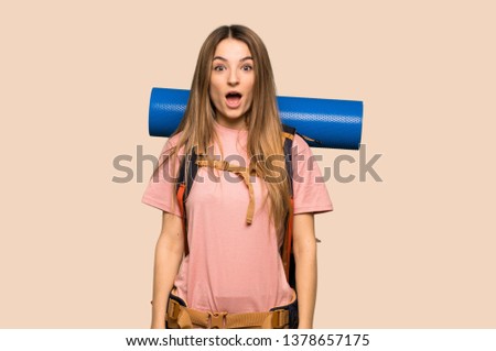 Young backpacker woman with surprise and shocked facial expression on isolated yellow background