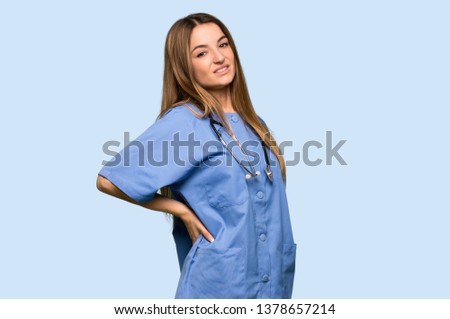 Young nurse suffering from backache for having made an effort on isolated blue background