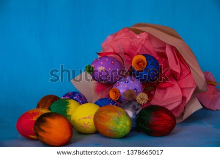 A bright Easter composition consisting of hand-painted eggs and a beautiful bouquet of three colored eggs with dry grass and decorative elements.