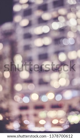 Blurred illuminated building at night, color toned abstract urban background.