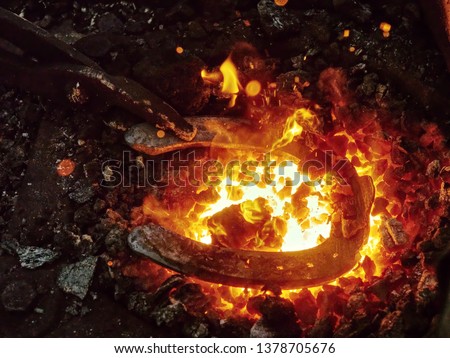 Detail of blacksmith forge with shinning and glowing steel horseshoe. Traditional farrier craftsmanship  Royalty-Free Stock Photo #1378705676