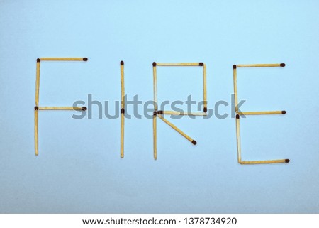 The word fire is laid out from matches on a blue background