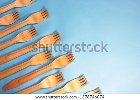 Disposable ecological wooden bamboo fork and spoon pattern on a blue background. Environment friendly flat lay with free copy space for text. Selective background