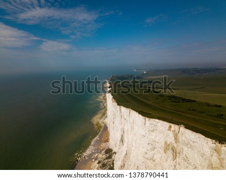 Sheer drop off from the green grass to the white cliffs leading to blue water in England