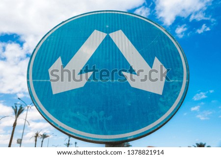 Round blue road sign with white diagonal warning arrows.