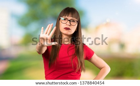 Woman with glasses making stop gesture denying a situation that thinks wrong at outdoors