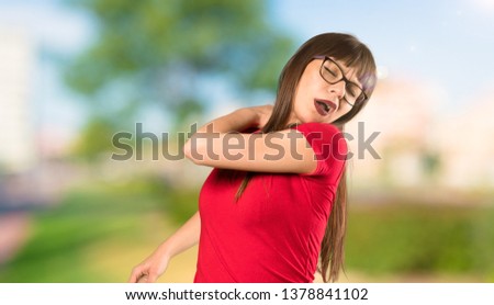 Woman with glasses suffering from pain in shoulder for having made an effort at outdoors