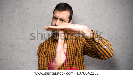 Man with shopping bags making stop gesture with her hand to stop an act over textured wall