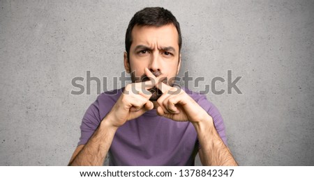 Handsome man showing a sign of silence gesture over textured wall