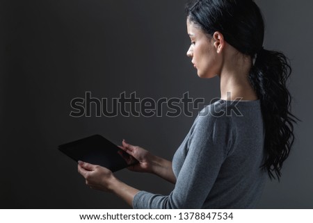 Young woman using her tablet on a gray background