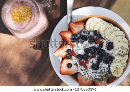 Healthy tropical breakfast bowl: blueberry smoothie with banana, strawberry, açaí, nuts, sunflower and chia seeds. Healthy food concept. Flat lay, top view, close up