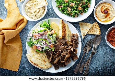 Mediterranean food on the table, gyro platter, pita and dips and tabbouleh Royalty-Free Stock Photo #1378895795