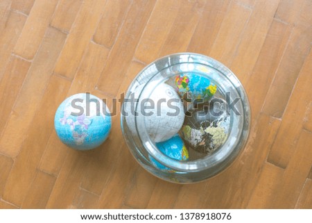 Many globes are in glass bottles. But with one globe on a brown wood floor
