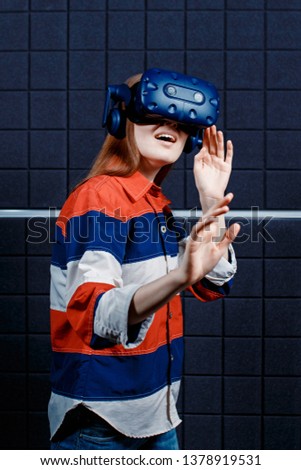 A young girl in a virtual reality club plays video games. Emotion of surprise.