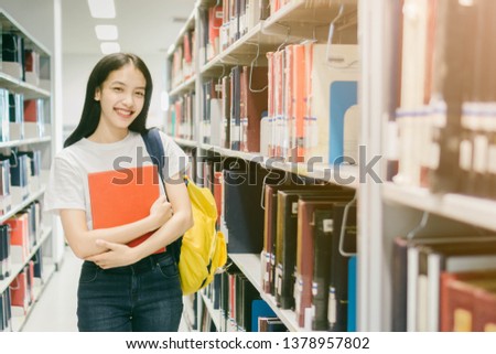 Portrait of young Asian woman with a book in library,Education Concept.