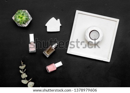 perfume, nail polish, candle, concrete figures and tray decorations for morden home office on black background flat lay