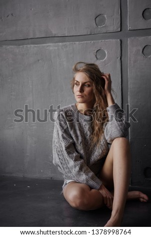 Beautiful girl sitting on the background of a concrete wall